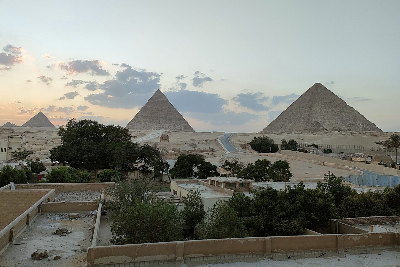 La puesta de sol frente a la Esfinge y las Pirámides desde el balcón en la habitación del hotel de Guiza. Egipto.
